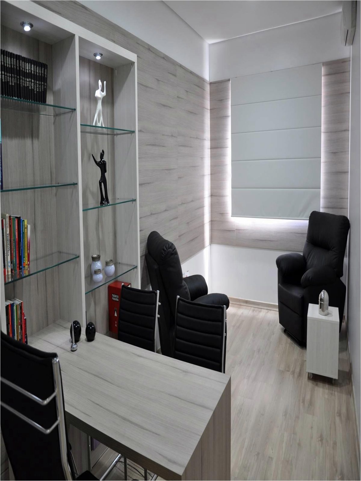 Consultório com mesa de atendimento e estante planejadas